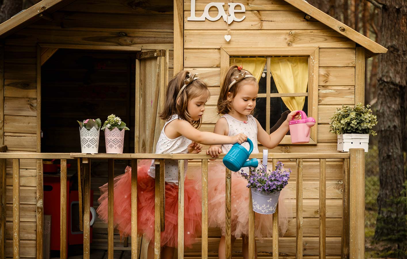 Ein Spielhause ist etwas ganz besonderes für ein Kind. Zwei Mädchen gießen die Blumen vor ihrem Spielhaus